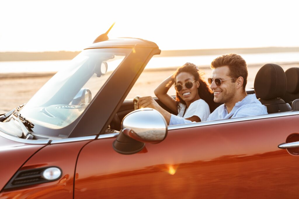 Image of young multiethnic couple man and woman smiling while driving convertible as they explore the best things to do in Mississippi for couples