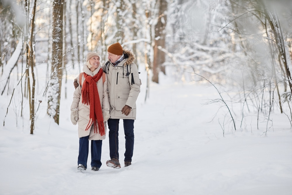 A senior couple walking through the trees during their wisconsin winter getaway
