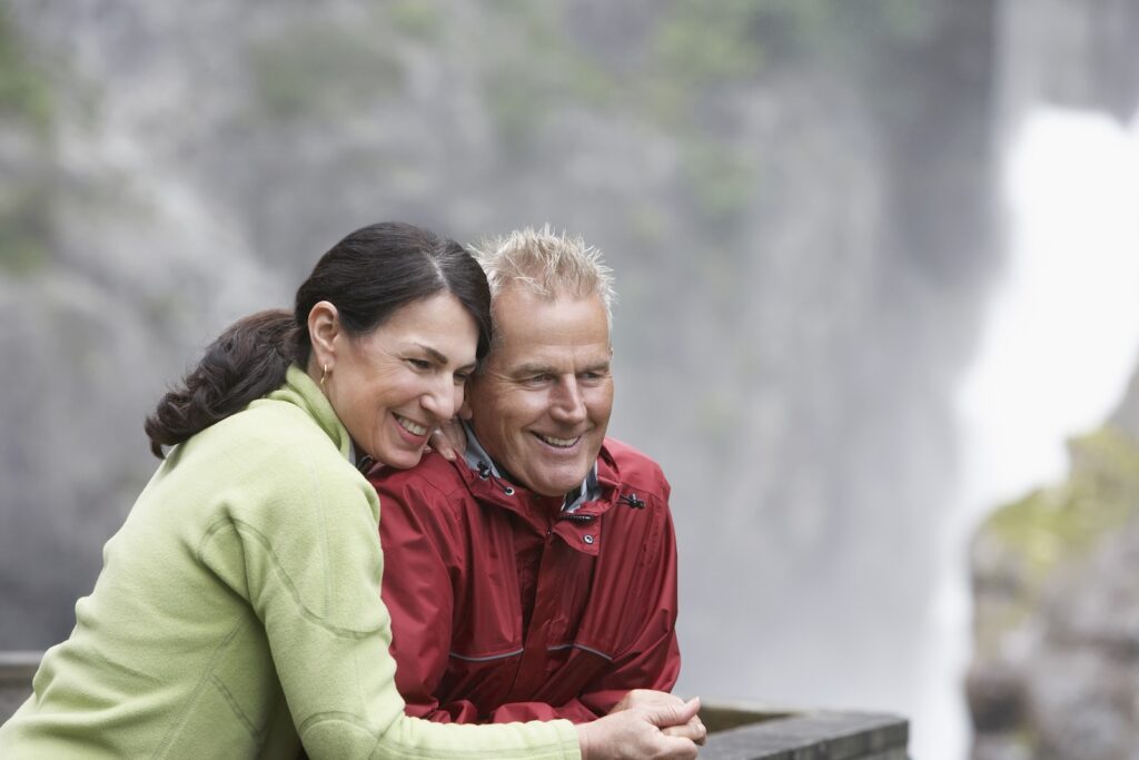 Happy middle aged man and woman looking at Moss Glen Falls in Vermont