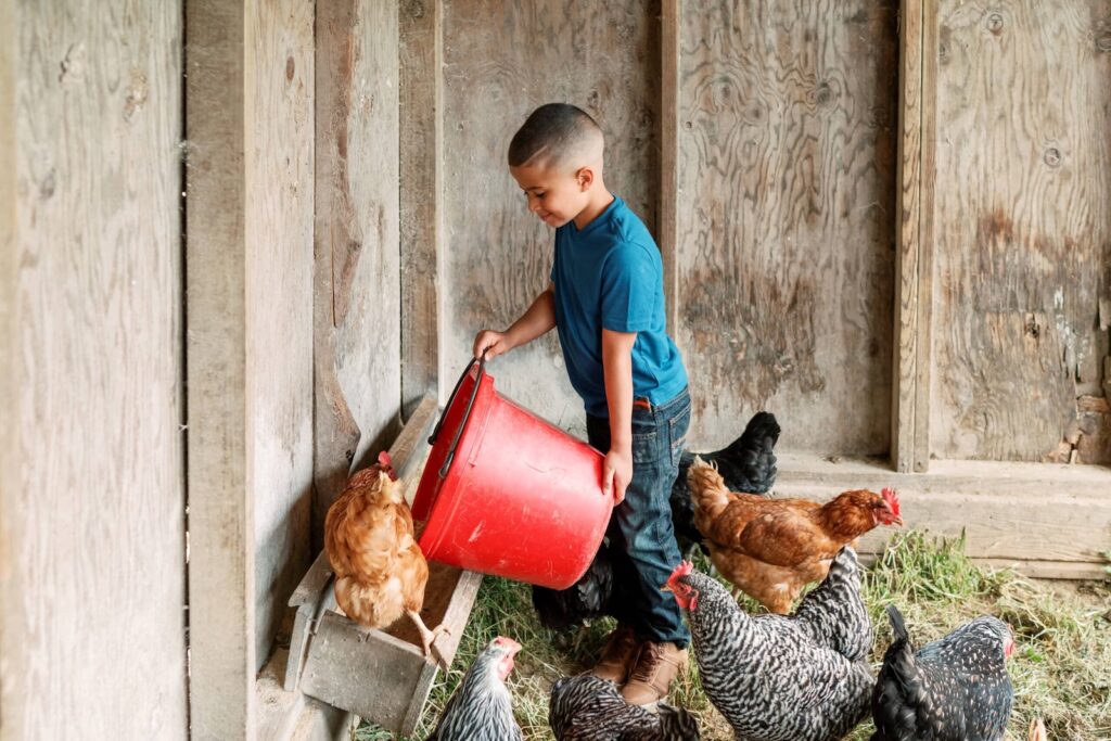 Discover family farm stays near Philadelphia with hands-on experiences, farms in Lancaster PA, and family-friendly farm stays in Pennsylvania. Photo of a kid feeding chickens at the farm