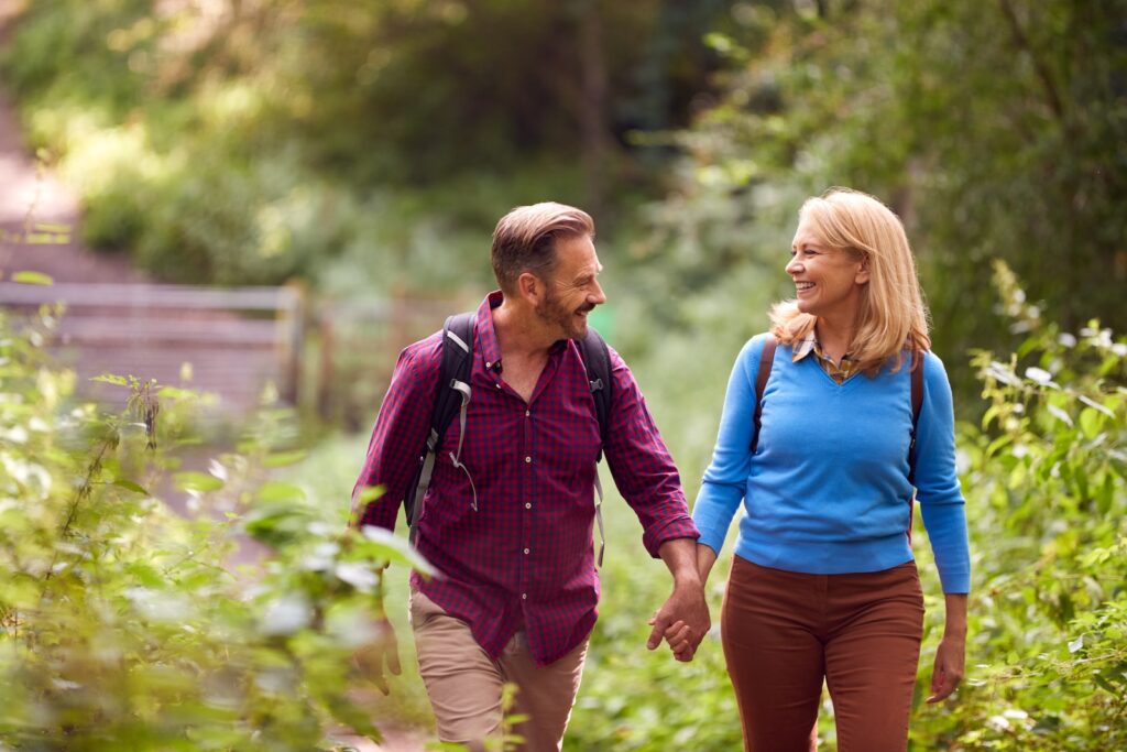 Mature Loving Couple In Countryside Hiking Along Path Through Forest Together Holding Hands, hocking hills hiking at its best
