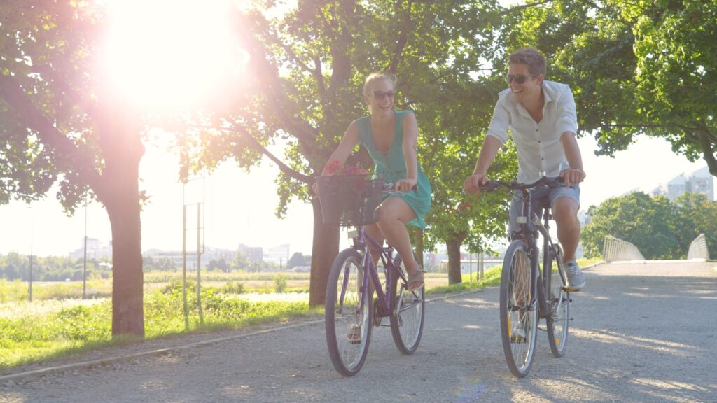 Cheerful couple enjoy a sunny summer day by riding bikes around the park on the best Madison bike trails