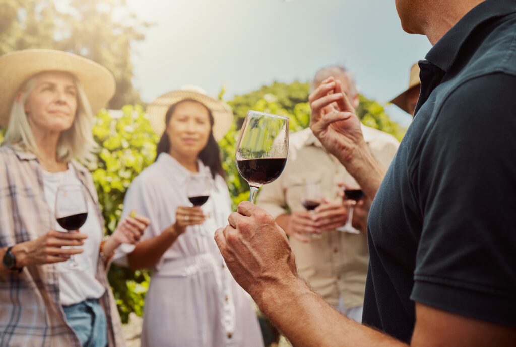 Small group in vineyard holding wine glass, tasting wine at Fox Run Vineyards in the Finger Lake Wine Country