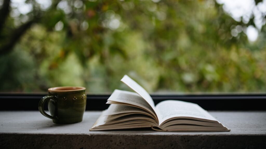 After shopping at Eagle Harbor Books, relax with a cup of coffee. Open book, mug on table in front of window overlooking trees.