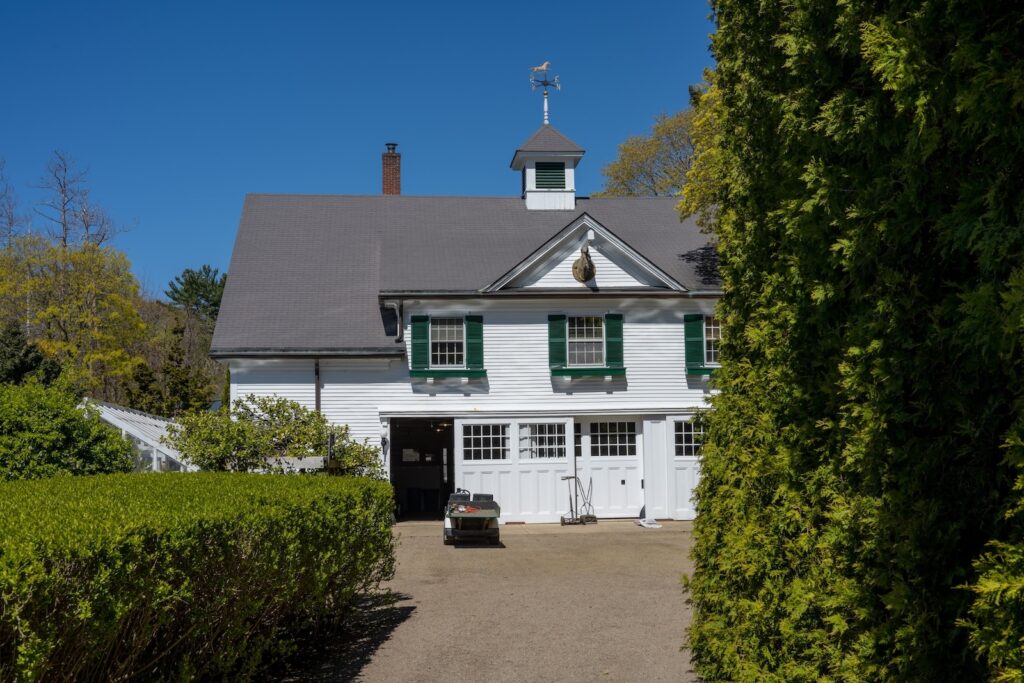 A white building framed by hedges at the Fuller Gardens in New Hampshire.