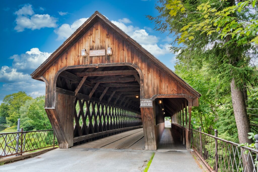 A wooden covered bridge on a sunny day, what you can find when exploring things to do in Vermont.