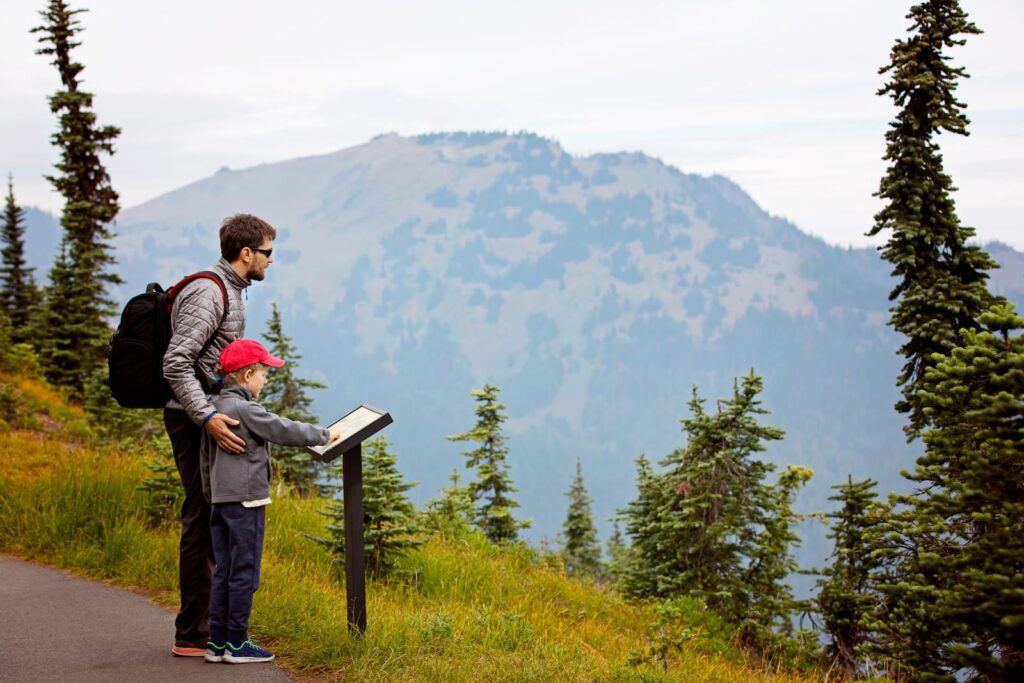 A father and son read a marker by a mountain in the Olympic National Park, one of the fun things to do in Sequim with kids.