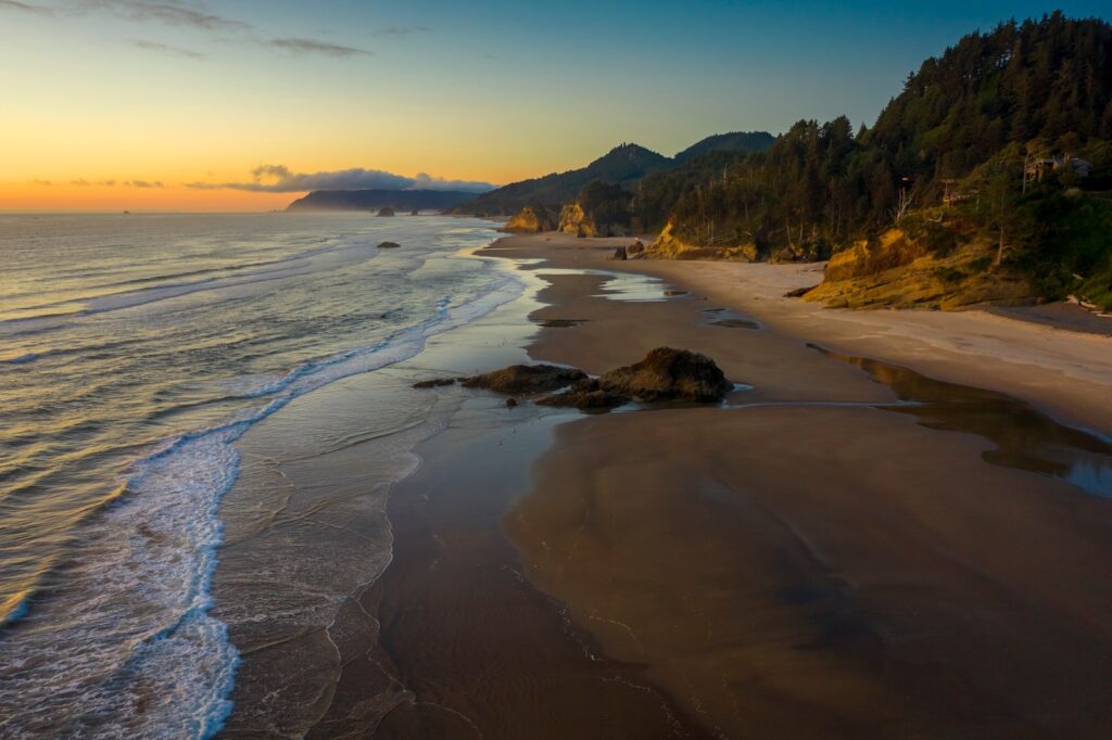 Aerial View of Arch Cape, Oregon. Sunset along the Oregon coast near Cannon Beach features white sand Oregon beaches with fir and cedar forests as far as the eye can see.
