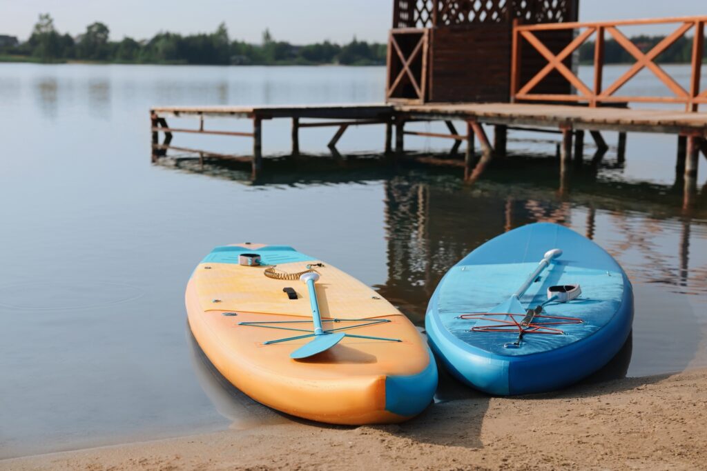 Yellow and blue paddle boards by a dock on a sandy lake shore at Farmington Lake in New Mexico.