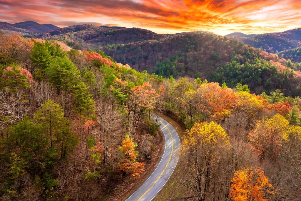 Vibrant autumn landscape in North Carolina mountains. Fall colors stretch across hillsides along quiet mountain road on the Blue Ridge Parkway.