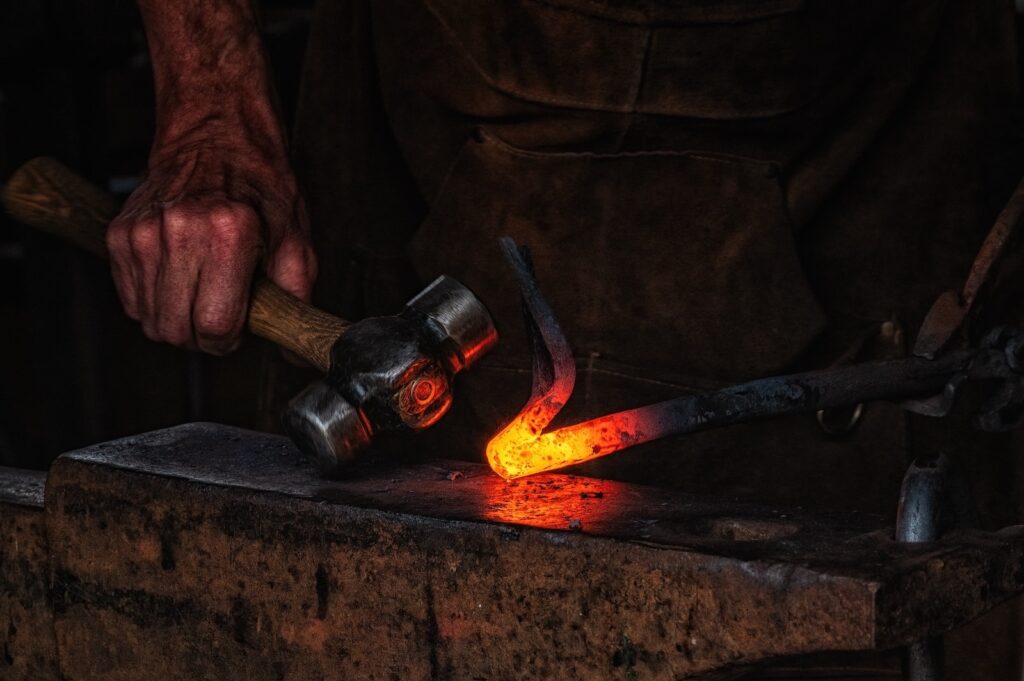 A blacksmith manually forging the molten metal on the anvil at the Old Blacksmith Shop in Galena, IL.