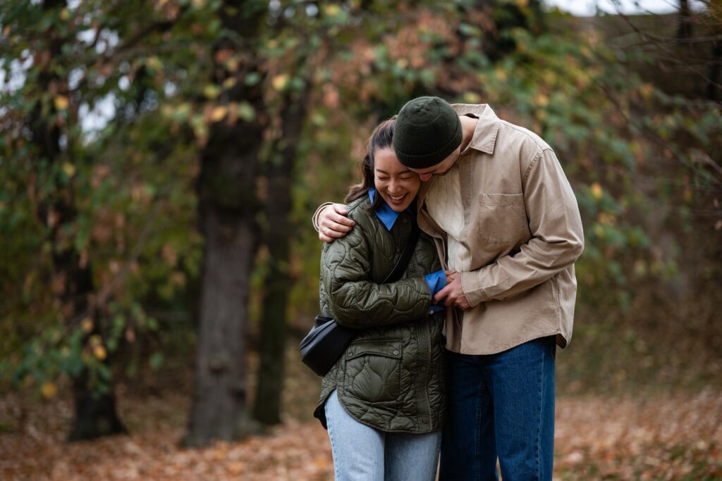 Young couple embracing and laughing outdoors, enjoying one of the most romantic getaways in NC in the fall.