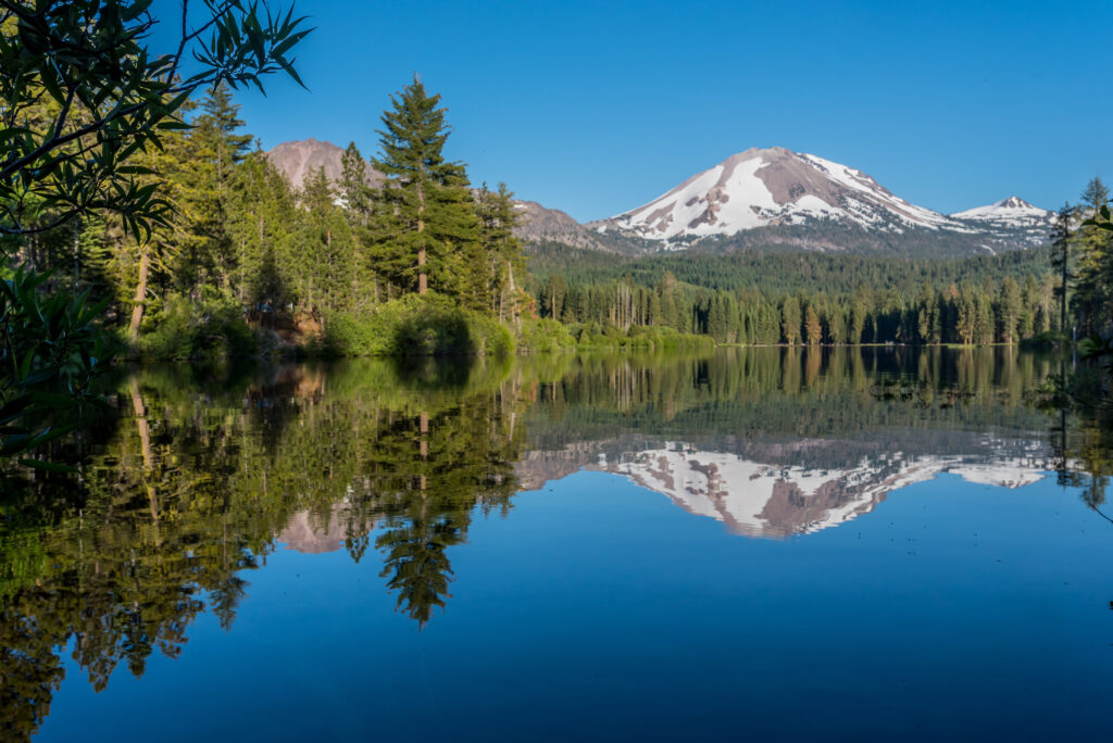 Lassen Peak reflected in the calm waters of Manzanita Lake in Lassen Volcanic National Park.