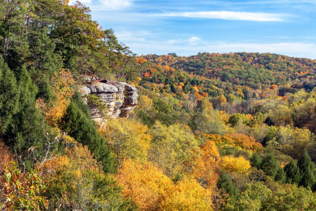 The southwestern Ohio autumn landscape is painted with the colors of fall leaves as viewed high above the trees and rock walls of Conkle’s Hollow in the beautiful Hocking Hills. One of the best Hocking Hills adventures