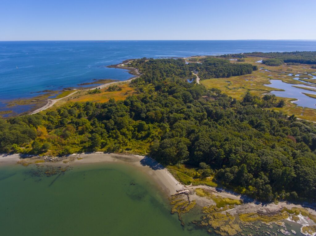 Aerial view of Odiorne State Park in summer in town of Rye, NH, with trees, beach and ocean.