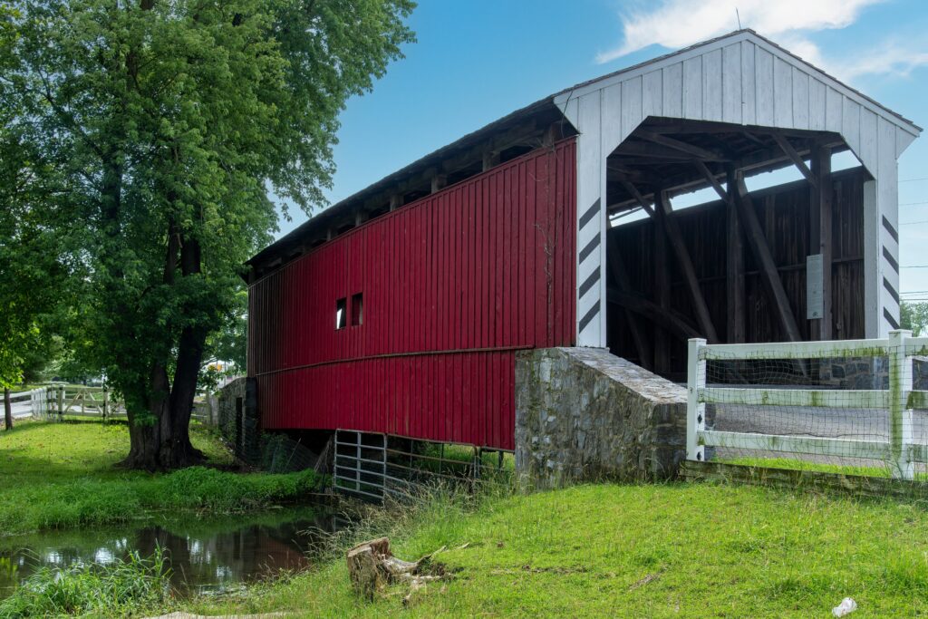 Visiting covered bridges is one of the top things to do in Intercourse PA. Historic red covered bridge over river