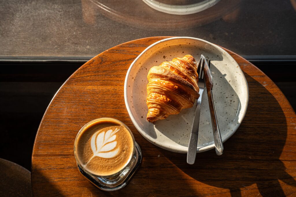 Latte and croissant on table at coffee shops on Bainbridge Island