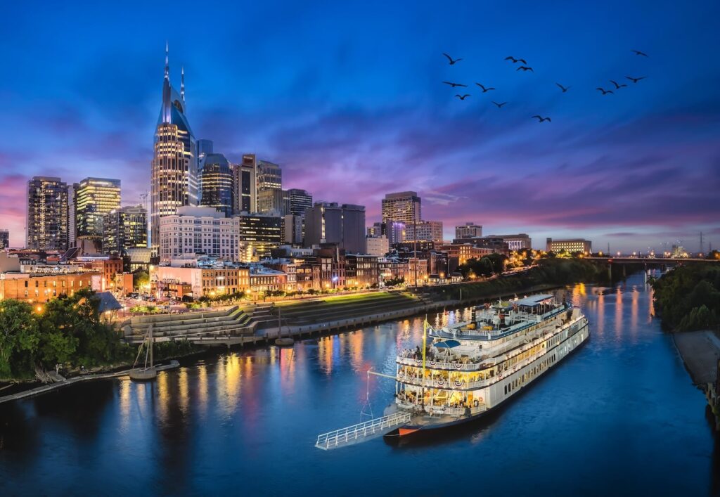 Where to stay in Nashville: the downtown skyline and a riverboat on the Cumberland River at dusk
